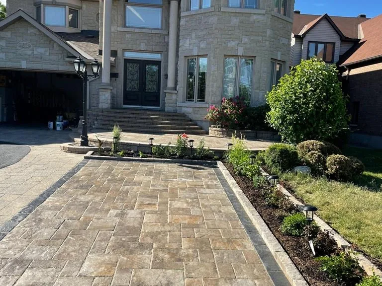 Interlock paver driveway and garden beds installed at a stone-front Ottawa home